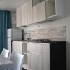 Cucina moderna con mobili chiari e tendine blu.
