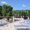 Sdraio blu a righe bianche su una terrazza, alberi e bandiere sullo sfondo.