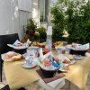 Tavola all'aperto con colazione abbondante e cane sullo sfondo.