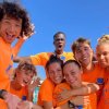 Gruppo di persone sorridenti in magliette arancioni.