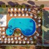 Vista aerea di una piscina circondata da ombrelloni e campo da tennis.
