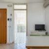 Stanza luminosa con tavolo, sedie e piccolo televisore.