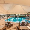 Tavoli sotto un tendone affacciati su una piscina.