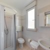 Bagno con doccia, WC e lavabo, finestra accanto.
