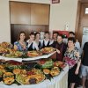 Tavolo con vassoi di frutta e persone sorridenti.