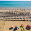 Spiaggia affollata con ombrelloni e giochi per bambini.