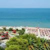 Spiaggia affollata con ombrelloni colorati e mare azzurro.