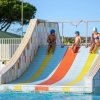 Tre bambini scendono uno scivolo colorato in piscina.