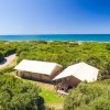 Due tende glamping tra la vegetazione con vista sull'oceano.