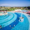 Ampia piscina con fontana centrale e molte persone che nuotano.
