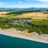Veduta aerea di una spiaggia, campagne e un resort circondato da alberi.