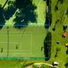 Campo da tennis e da calcio con un'area giochi verde accanto.