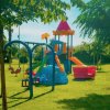 Parco giochi colorato con altalene e scivolo su prato verde.