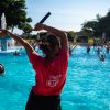 Una persona con una maglietta rossa guida attività in piscina.