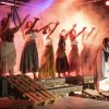 Persone sul palco che alzano le braccia in una performance teatrale.