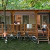 Famiglia e biciclette su un patio davanti a una roulotte in legno.