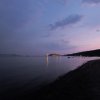 Tramonto su una spiaggia con luci in lontananza.