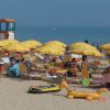 Spiaggia affollata con ombrelloni gialli e persone in relax.