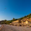 Spiaggia con case e scogliera al tramonto.