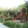 Parco giochi con scivolo tra gli alberi.