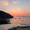 Tramonto sul mare con piscina e sedie a sdraio.