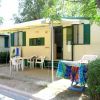 Una casa mobile con veranda coperta, sedie e tavolo all'aperto, circondata da alberi.