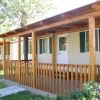 Una casa mobile con veranda coperta in legno, circondata da vegetazione.