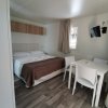 Camera moderna con letto matrimoniale, tavolo e sedie bianche, pavimento in legno.
