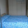 Camera da letto con letto matrimoniale coperto da trapunta blu e armadio bianco.
